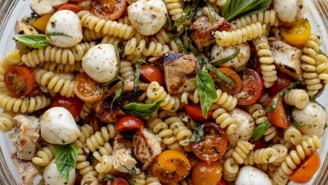 Grilled chicken over rainbow caprese pasta salad with balsamic glaze drizzle